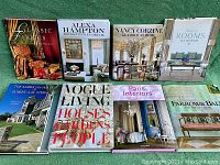 Photo showing eight hardcover books on interior design and related subjects arranged on a green surface.