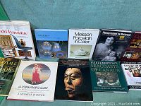 Photo showing a collection of 9 hardcover art and antiques books arranged upright, featuring photography and art on covers including porcelain, furniture, sculptures and Canadian themes.