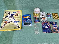 Image showing all items on a green cloth background, including anti-drug poster, Hot Wheels car, baseball, cards, and coins.