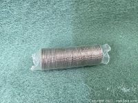 Full view of the tightly rolled bank fresh 2010 quarters sealed in clear plastic wrapping on green felt background