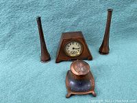 Full view of all items: triangular copper clock in center, two tall copper vases on sides, copper inkwell in front