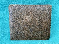 Brown textured cover of album, shows pebbled faux-leather and gold embossed title “Cigarette Album.”