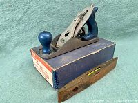 Overall lot showing Hoppe wood plane on box next to antique level