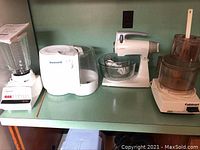Osterizer blender with glass pitcher, Honeywell humidifier, Sunbeam Mixmaster hand mixer with glass bowl, and Cuisinart food processor on countertop.