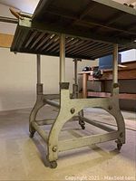 Side angle view of the industrial roller table showing metal rollers, vertical supports, and caster wheels.