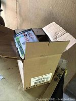 Open cardboard box containing smaller boxes of light bulbs visible inside