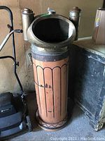 Front view of wooden and brass binnacle showing slatted veneer exterior and brass top