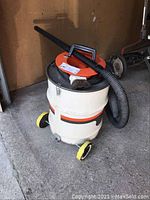 Full image of the Black & Decker shop vacuum with hose and attachments showing overall condition and setup.