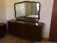 Wooden dresser with nine drawers and attached large mirror, showing overall style and condition