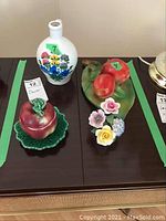 View of all three decorative ceramic items arranged on a dark wooden surface.