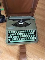 Front view of Hermes Baby typewriter showing mint-green body and turquoise keys