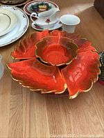 Close-up of bright orange-red ceramic sectional hors d'oeuvres tray with gold accents shaped like leaves