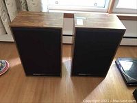 Two Marantz Distinction Series speakers with wooden cabinet and black front grille covers showing the model name.