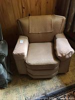 Front angle photo of the large beige sofa chair with textured fabric, armrest and backrest covers visible.