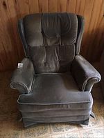 Front angled view of a dark green fabric sofa rocking chair, showing wear on fabric and padded armrests.