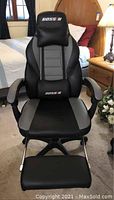 Front view of Bossin gaming chair showing black and gray leather upholstery, high backrest with head and lumbar support cushions embroidered with 'BOSSIN'.