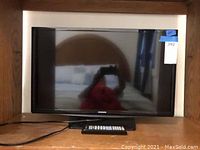 Front view of Samsung 27-inch LED TV with screen off, showing size and model style with reflected room background.