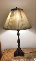 Full view of tall table lamp with pleated shade on a wooden surface.