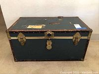 Front view of vintage travel trunk showing metal clasps and lock.