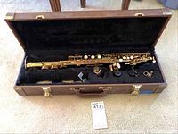 Soprano saxophone body, neck, mouthpiece, ligature, cap arranged in open case