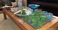Glassware and decor items on a wooden coffee table including blue candy bowl, green glass set, and ceramic starfish.