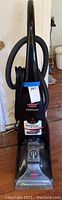 Front view of black Bissell Proheat Dirtlifter Powerbrush upright vacuum with hose coiled on side and control knob visible