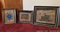All three Egyptian inspired framed wall hangings shown together on carpeted floor