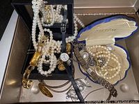 Photo showing the variety of women's wristwatches and assorted costume jewelry including pearl necklaces, gold-tone bracelets, and Neptune jewelry case with pearl jewelry inside.