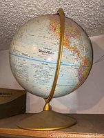 Front and side views of a 12-inch diameter Repogle World Nation Series globe on a golden metal base, showing detailed country names and borders.