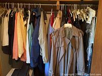 Wide view of assortment of jackets and coats hanging on a rod, showing different colors and styles including casual and formal.