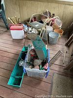 Photo showing assorted planters, wicker baskets, metal bucket, and step stool on porch floor.