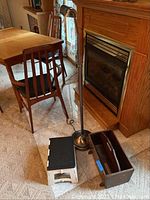 Metal floor lamp, white plastic folding step stool, and wooden magazine rack near fireplace and dining area