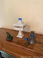Wide shot showing entire lot of seven items on wooden surface against cream wall including doorstop, candy dish and candle holders
