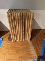 12 hardcover books forming a complete series set, standing upright on a wooden surface. Titles visible on spines.