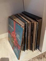Side view of multiple vintage vinyl records with diverse album covers, including one wrapped with a pink ribbon design.