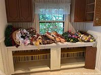 Photo showing a variety of decorative wreaths laid out on a tile counter, representing multiple seasons including spring, fall, Halloween, and winter.