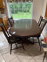 Full view of dark wood rectangular trestle dining table with four matching chairs in a kitchen area.
