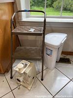 Wide view of the Cosco step stool, Sterilite trash can, and Oster food grinder as seen together in a kitchen setting.