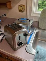 Cuisinart CPT-160 2-slice toaster and metal chafing dish on kitchen counter.