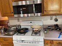 Stove top with a decorative ceramic bowl and metal baking pans on the counter