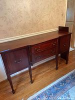 Front view of antique wooden sideboard with two dovetailed drawers and two side cabinet doors on four tapered legs.