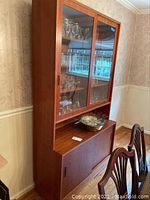 Front view of mid century modern wooden china hutch with glass sliding doors and lower sliding wood doors. Contents inside not included.
