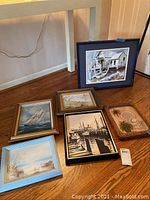Six framed ocean and shore themed artworks arranged on hardwood floor showing details and frames