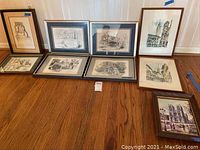 Overview image showing all nine framed artwork pieces arranged on a wooden floor, various historical and architectural prints mostly black and white.