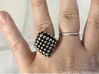 Silver vintage ring worn on finger showing beaded square face design.
