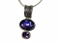 Close up of sterling silver pendant with abalone and faceted purple stone, showing detailed bail design and stone colors.
