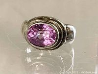 Front angle showing oval faceted pink stone set in sterling silver thick band ring.