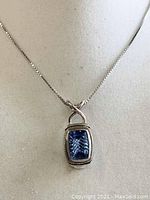 Front view of sterling silver pendant with rectangular blue gemstone on chain