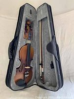 Eastar 1/4 size violin inside its open case with bow also fitted inside.