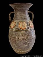 Full view of large terracotta planter with reddish shell motifs and two handles, shown on black background.
